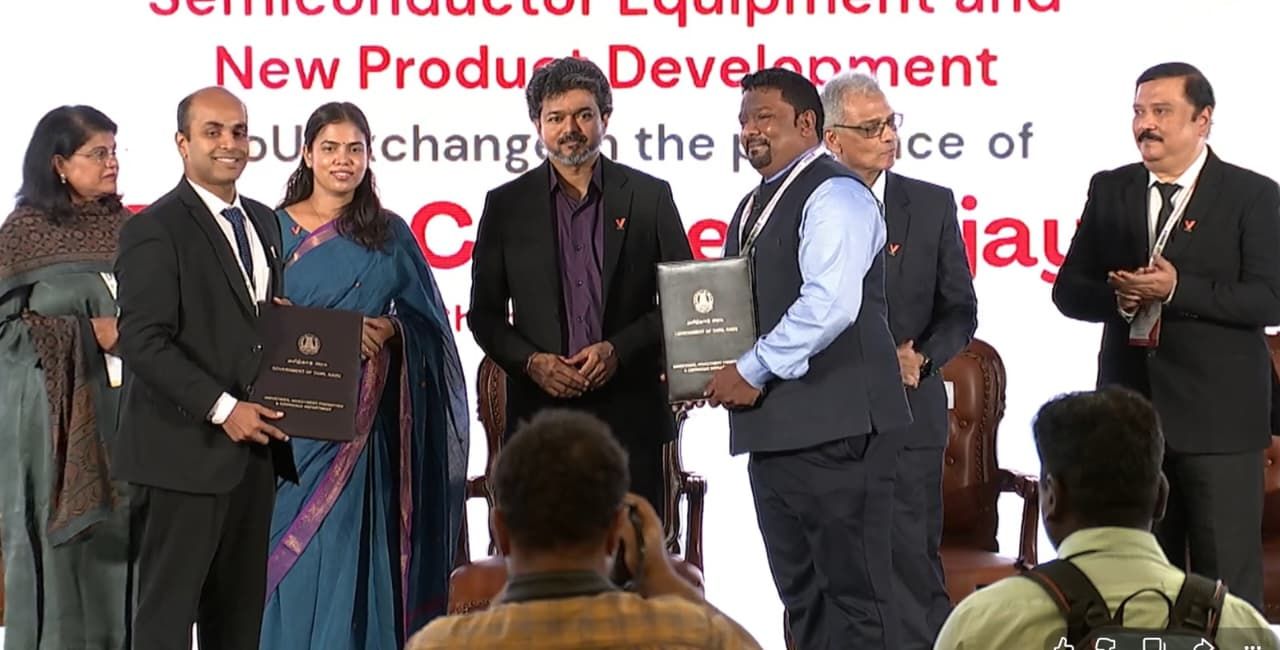 An agreement being exchanged on stage at a semiconductor equipment and new product development event
